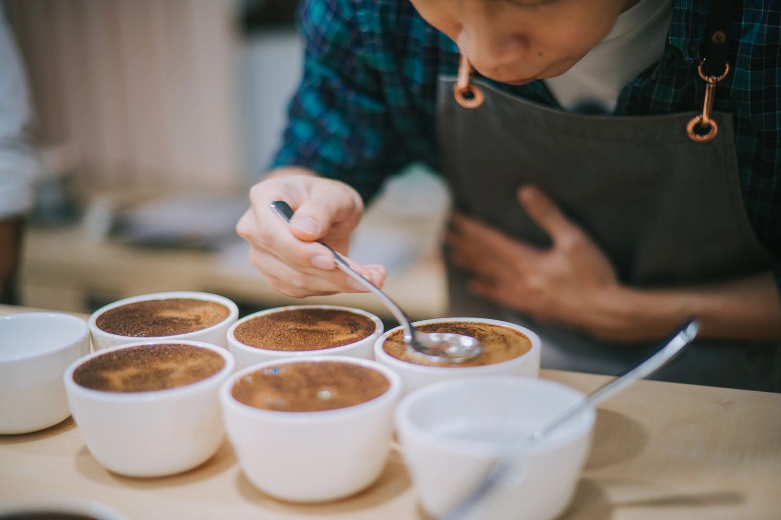Person tasting or testing multiple cups of coffee or similar beverage.