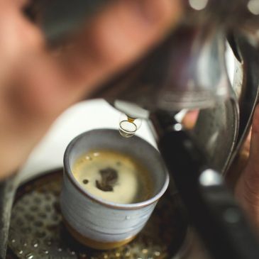 Close-up of espresso pouring into a ceramic cup from a machine.
